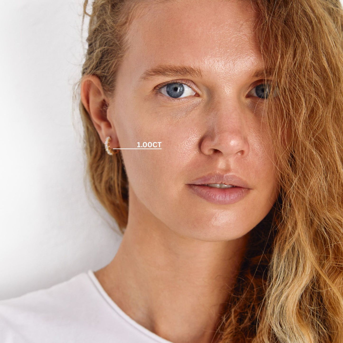 Woman wearing 1.00ct lab grown diamond huggie earrings in solid gold
