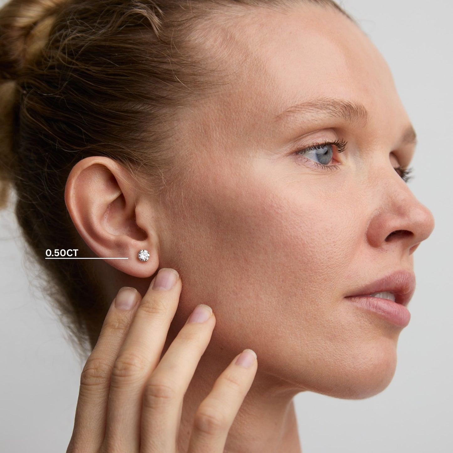 Woman wearing 0.50ct round lab grown diamond stud earrings in 9ct gold