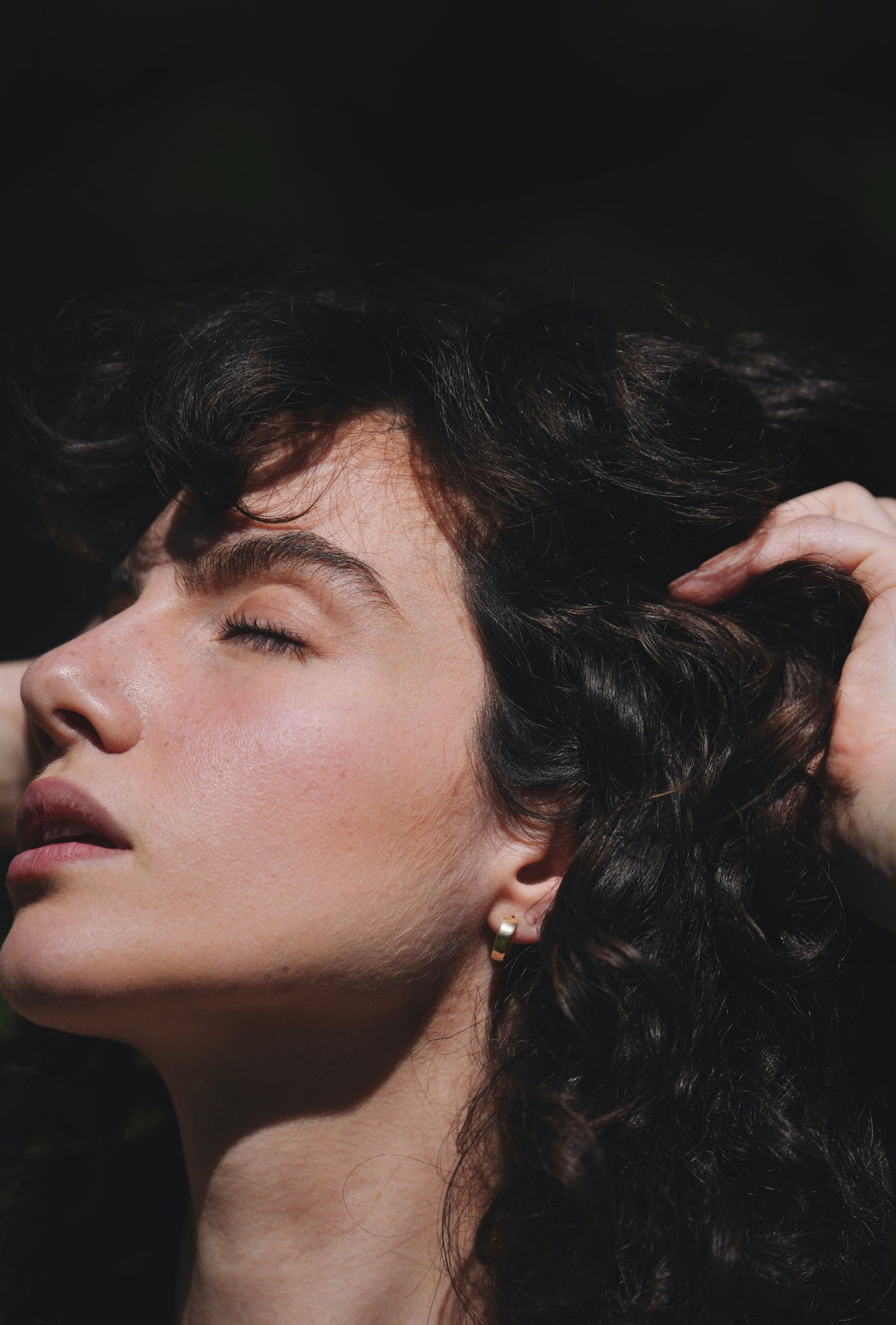 woman wearing solid gold wide huggie earrings