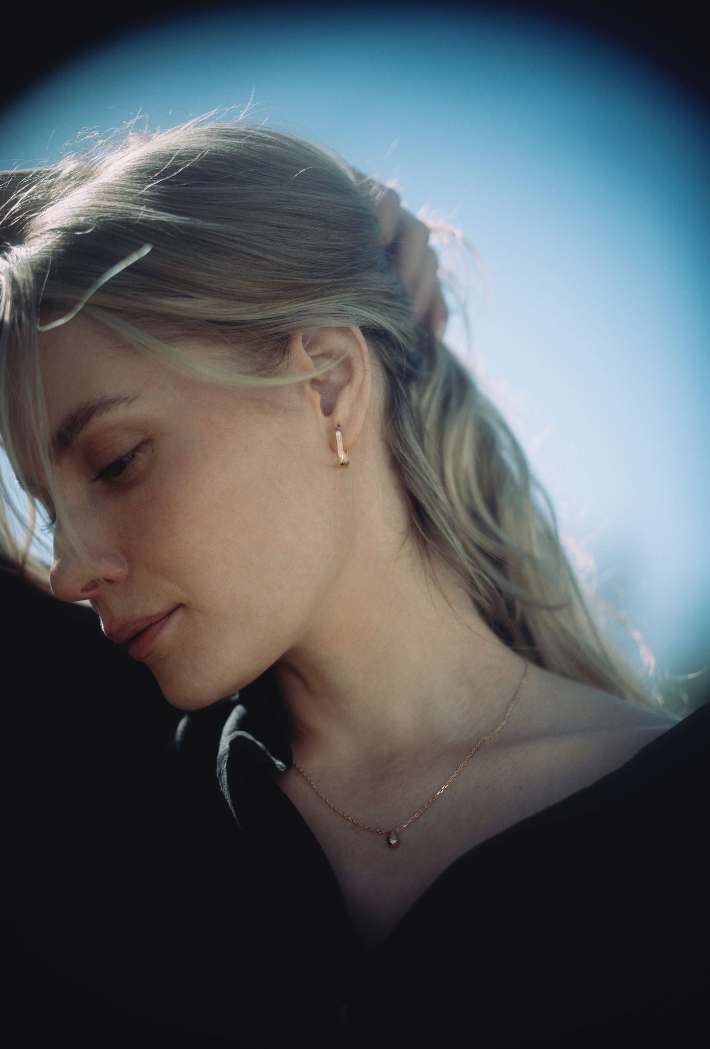 Woman wearing gold rectangle hoops and gold teardrop necklace