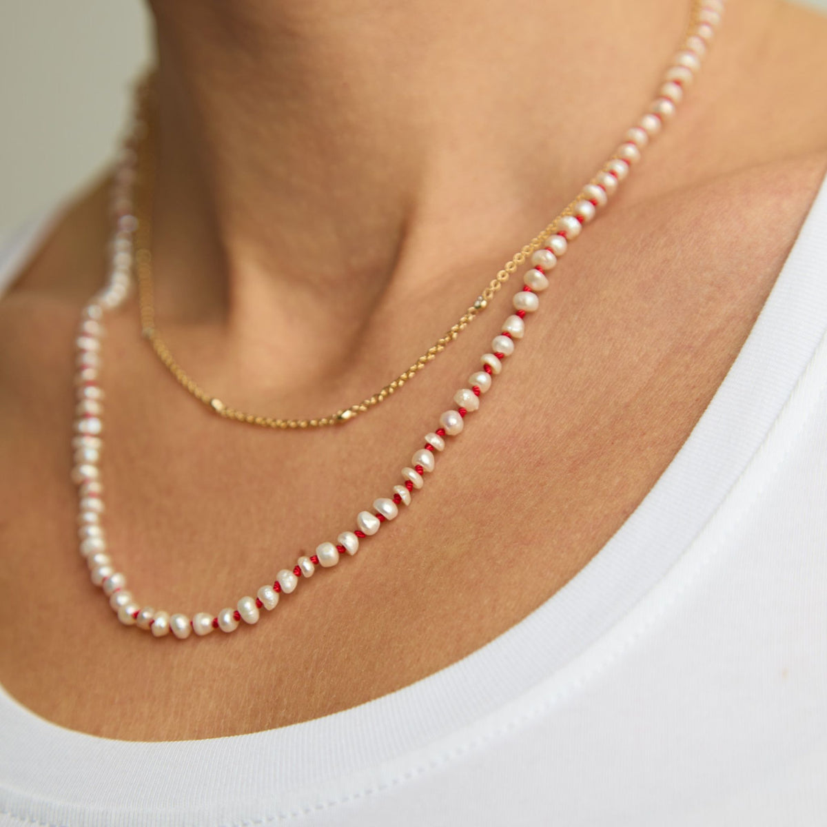 The Red Thread freshwater pearl necklace layered with a fine gold chain