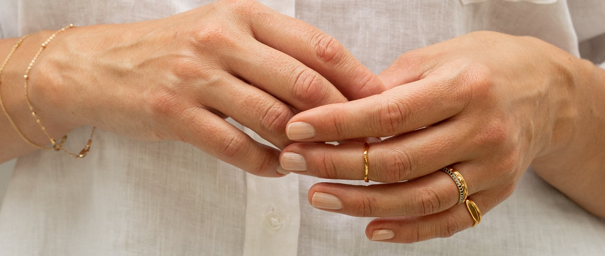woman's hand waering solid gold rings and bangles by Thor Collective