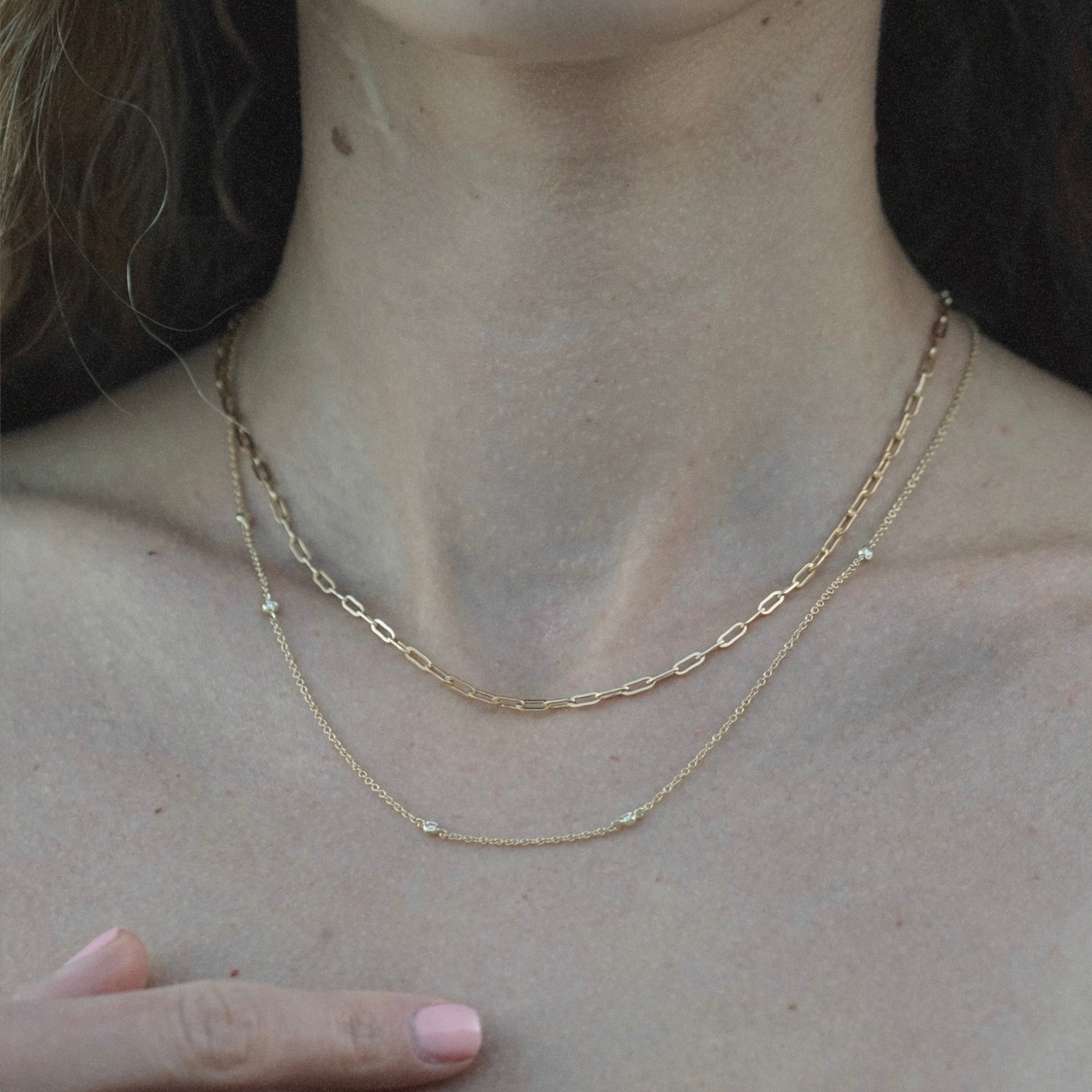 Woman wearing a fine natural diamond station necklace in yellow gold