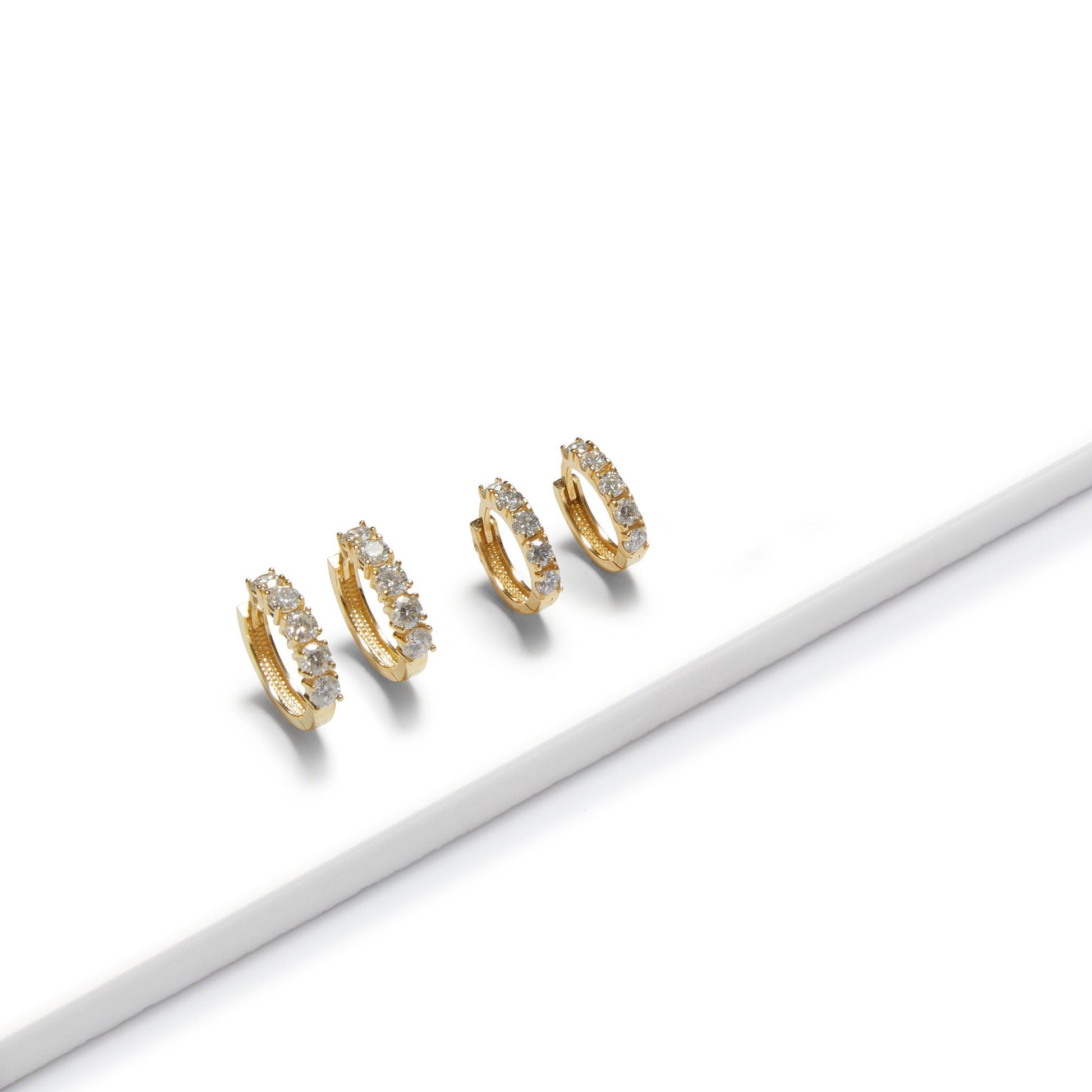 Pair of 9ct gold lab grown diamond huggie earrings displayed on white surface