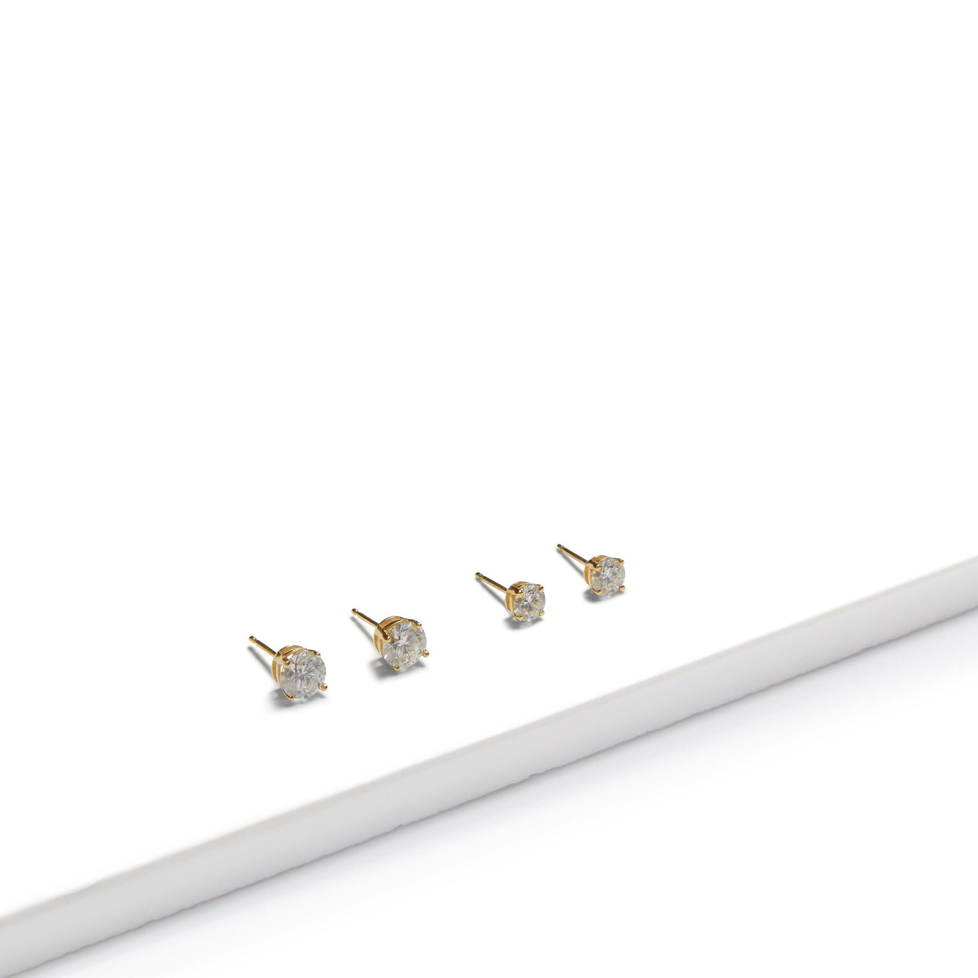 Pair of round lab grown diamond stud earrings in 9ct gold on white surface