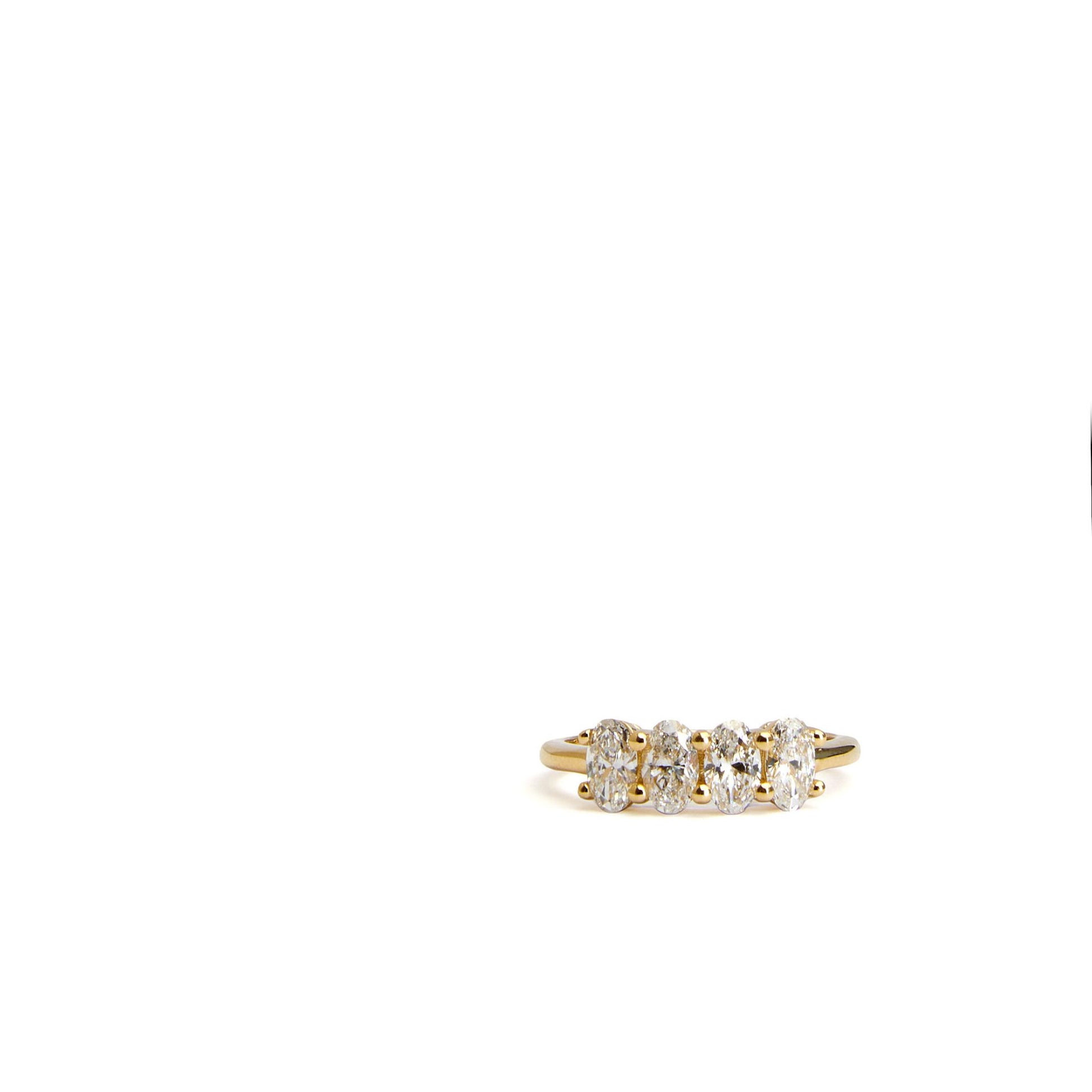 Four stone oval lab grown diamond ring in yellow gold on white background