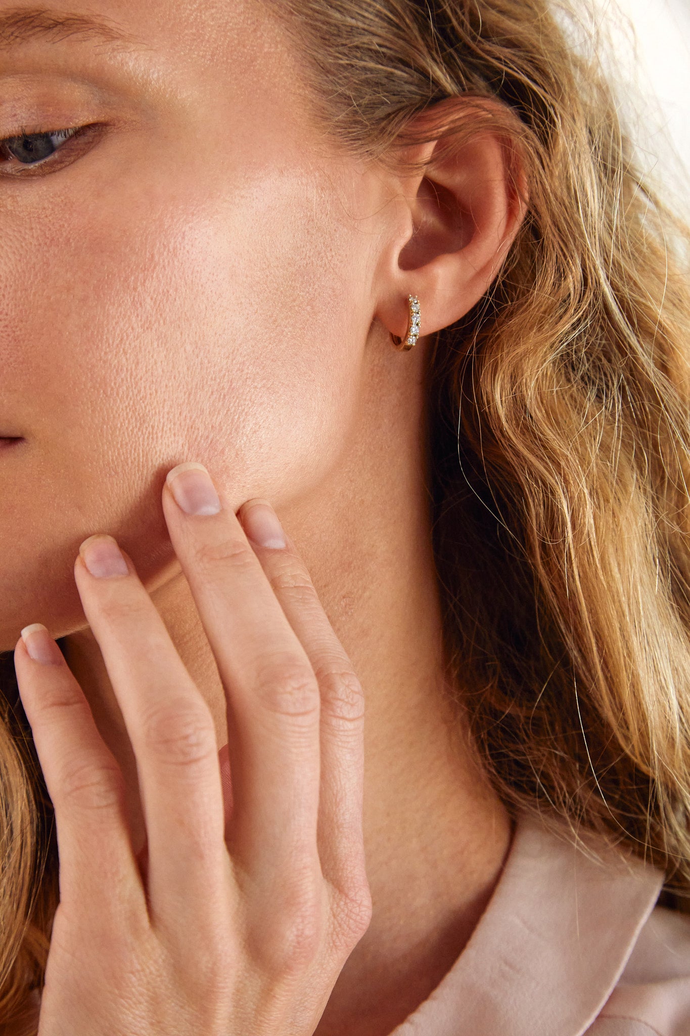 Close-up of woman wearing 9ct yellow gold lab-grown diamond huggie earrings from Thor Collective’s Modern Heirloom Collection.
