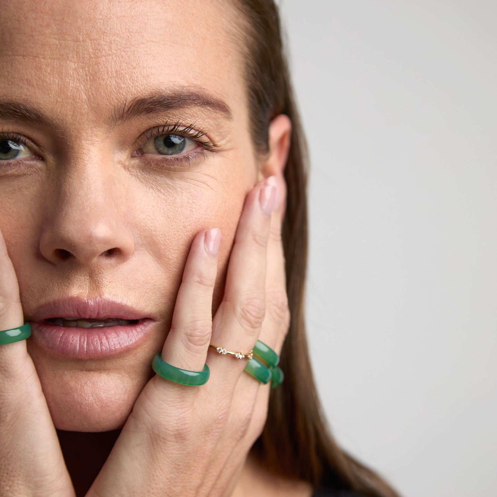 Woman wearing green agate cigar bands stacked on fingers