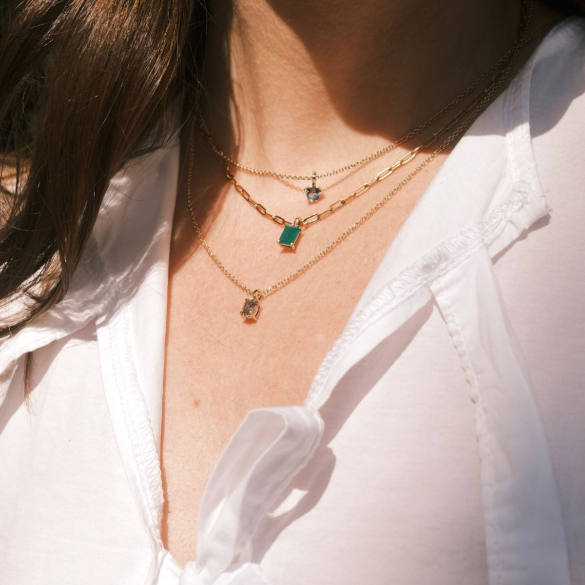 Green baguette gemstone pendant layered with fine gold necklaces