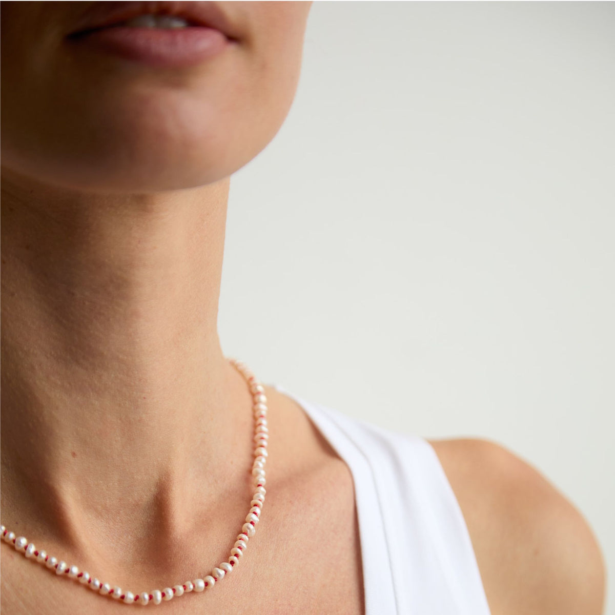 The Red Thread freshwater pearl necklace worn close to the neck